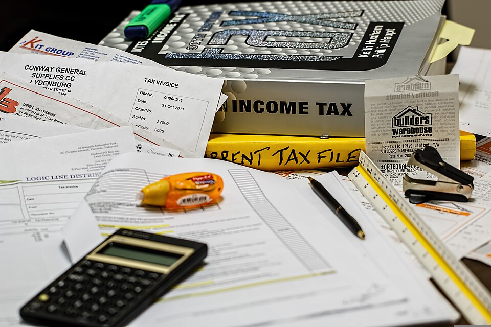 Stack of papers and tax documents Stack of papers and a book that is labeled 'Taxes"